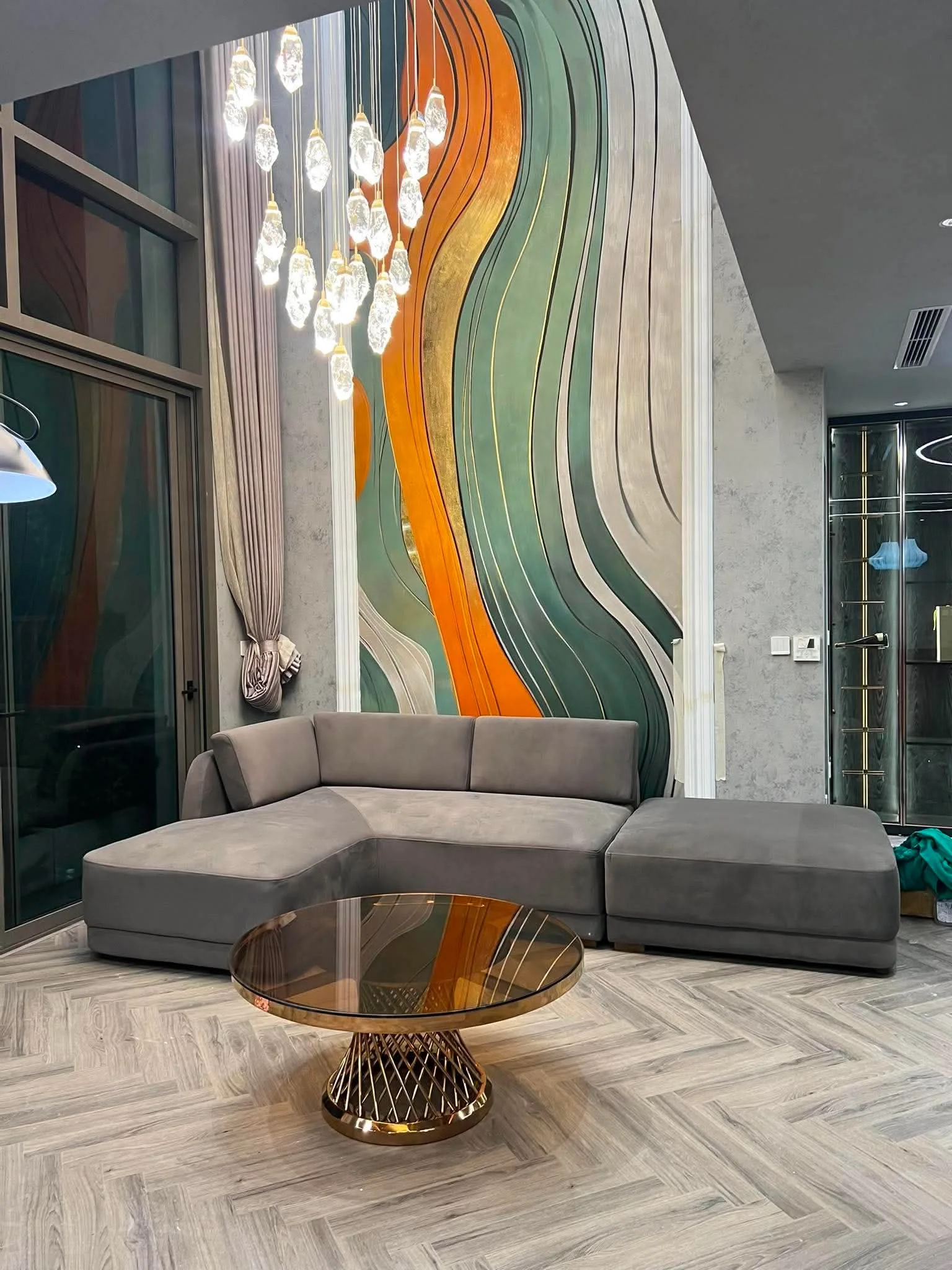 Phòng khách cao tầng với vách trang trí uốn lượn màu xanh cam phía sau sofa