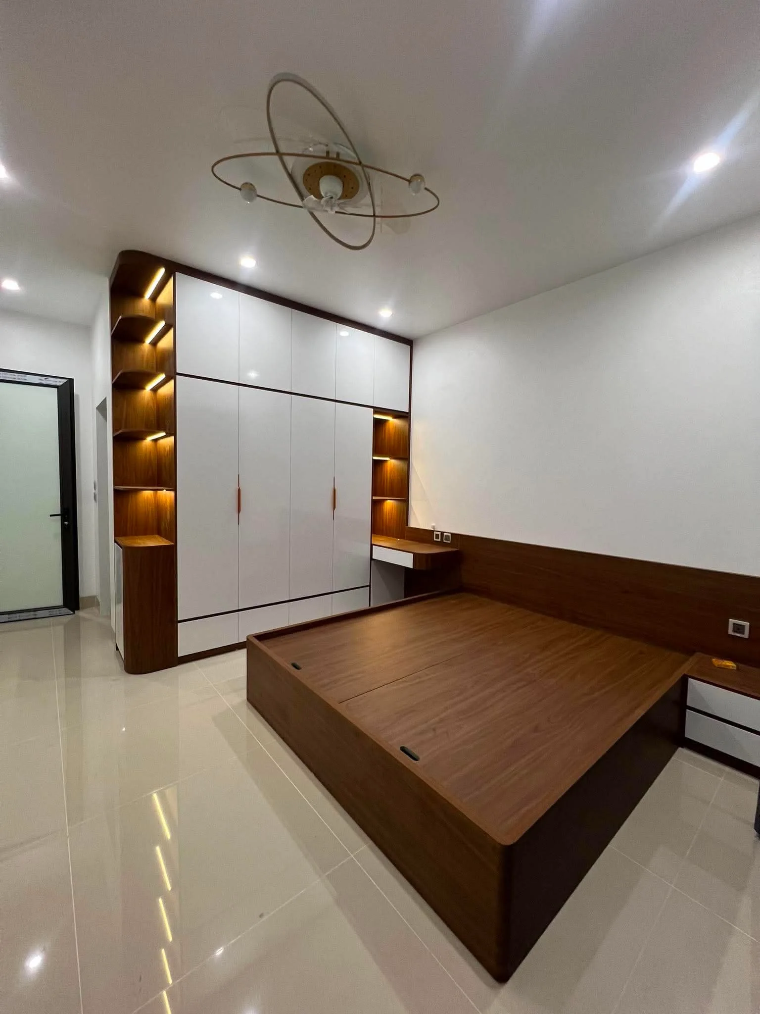 Phòng ngủ với giường gỗ, tủ áo trắng và các hốc trang trí ánh sáng vàng